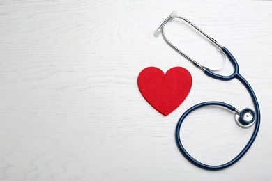 Stethoscope and red heart on white wooden surface, flat lay with space for text. Health insurance concept