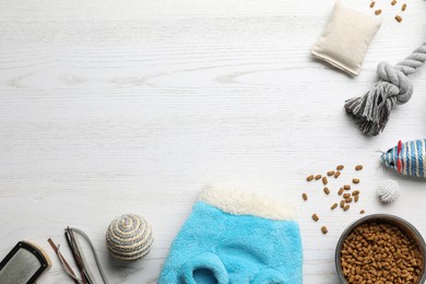 Photo of Flat lay composition with cat clothes, food and accessories on white wooden table. Space for text