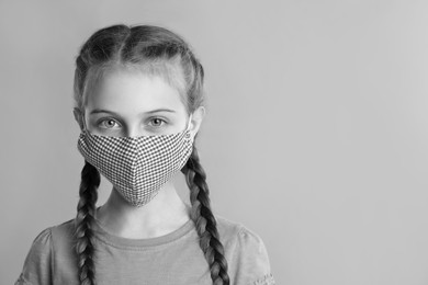 Girl wearing medical face mask on light background, space for text. Black and white photography