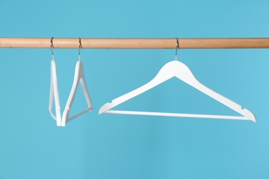 Photo of Wooden rack with clothes hangers on color background
