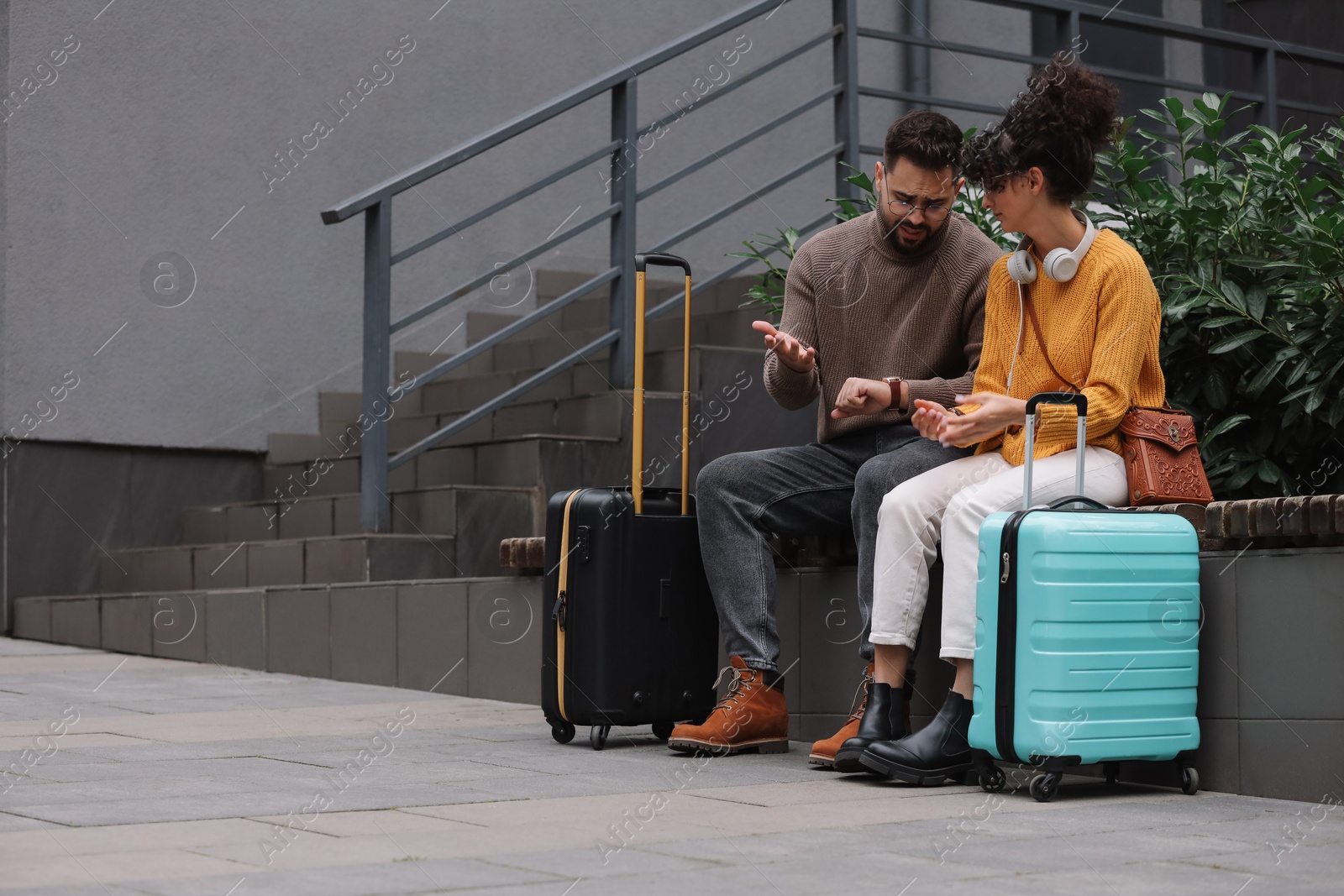 Photo of Being late. Worried couple sitting on bench outdoors