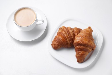 Fresh croissants and coffee on white background, above view. Tasty breakfast