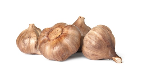 Unpeeled bulbs of black garlic on white background