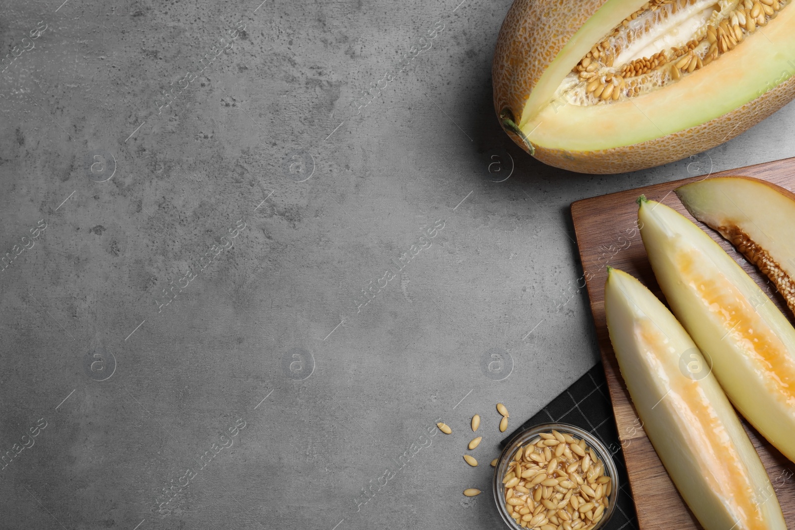 Photo of Slices of delicious honey melon on grey table, flat lay. Space for text