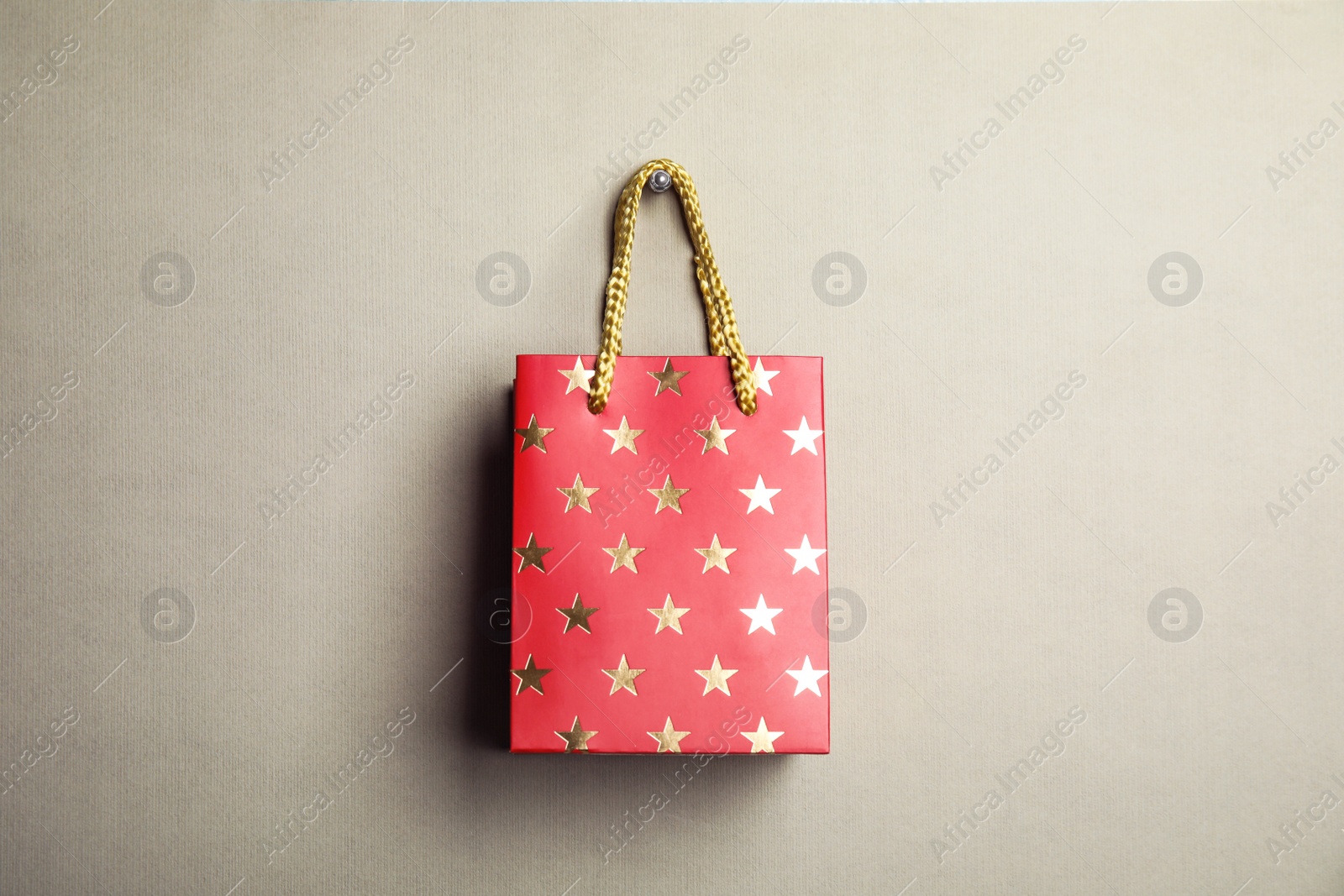 Photo of Red shopping paper bag with star pattern on grey background