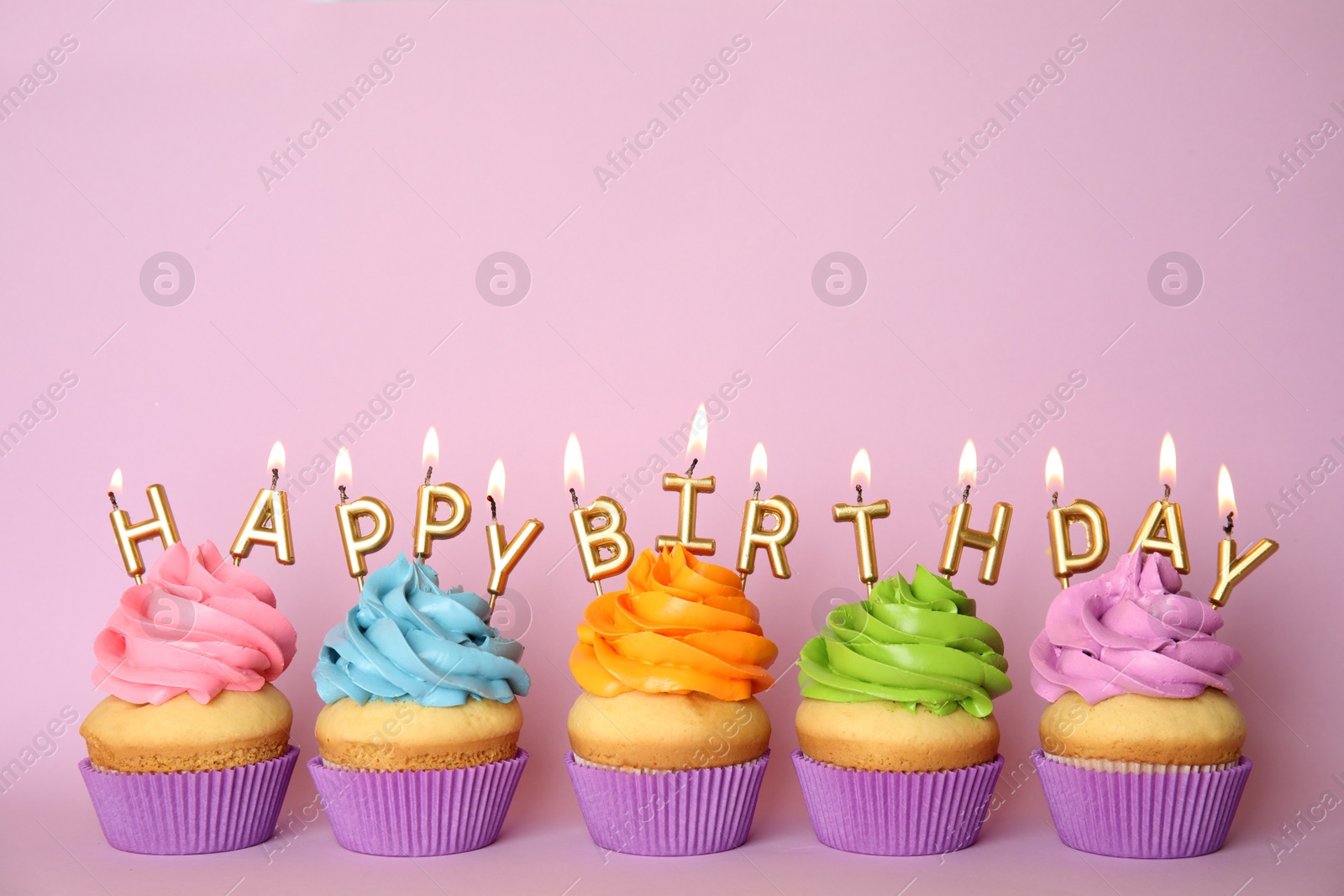 Photo of Birthday cupcakes with burning candles on pink background. Space for text