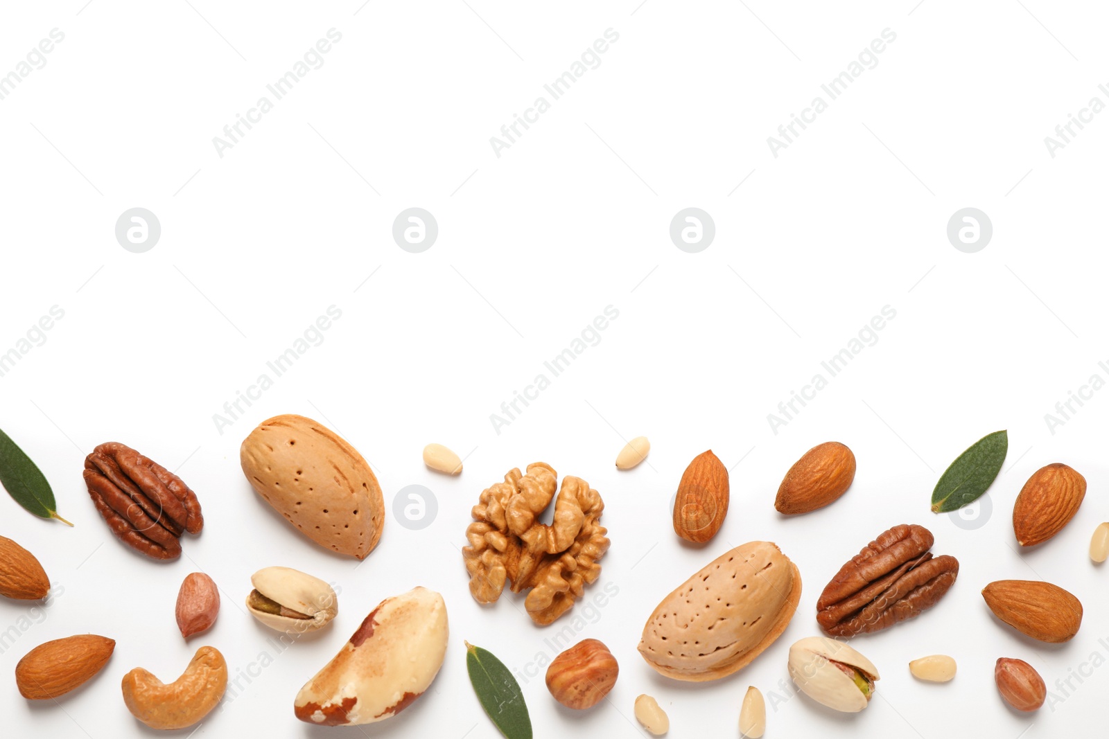 Photo of Different nuts and leaves on white background, flat lay. Space for text