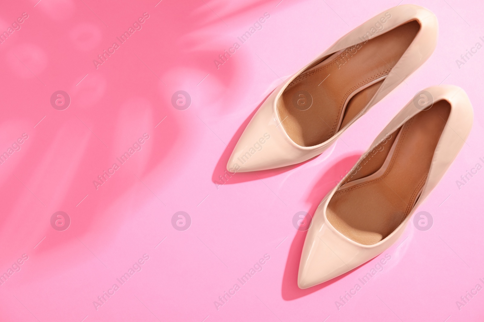 Photo of Pair of beautiful shoes, monstera leaf shade and space for text on color background, top view