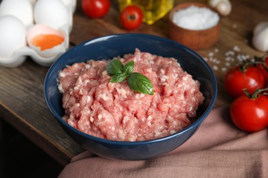 Photo of Raw chicken minced meat with basil and ingredients on wooden table, closeup