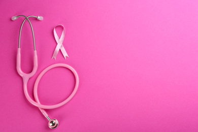 Pink ribbon as breast cancer awareness symbol and stethoscope on color background, flat lay. Space for text