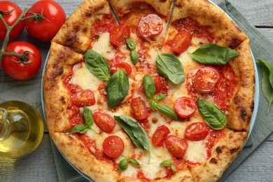 Delicious Margherita pizza and ingredients on gray wooden table, flat lay