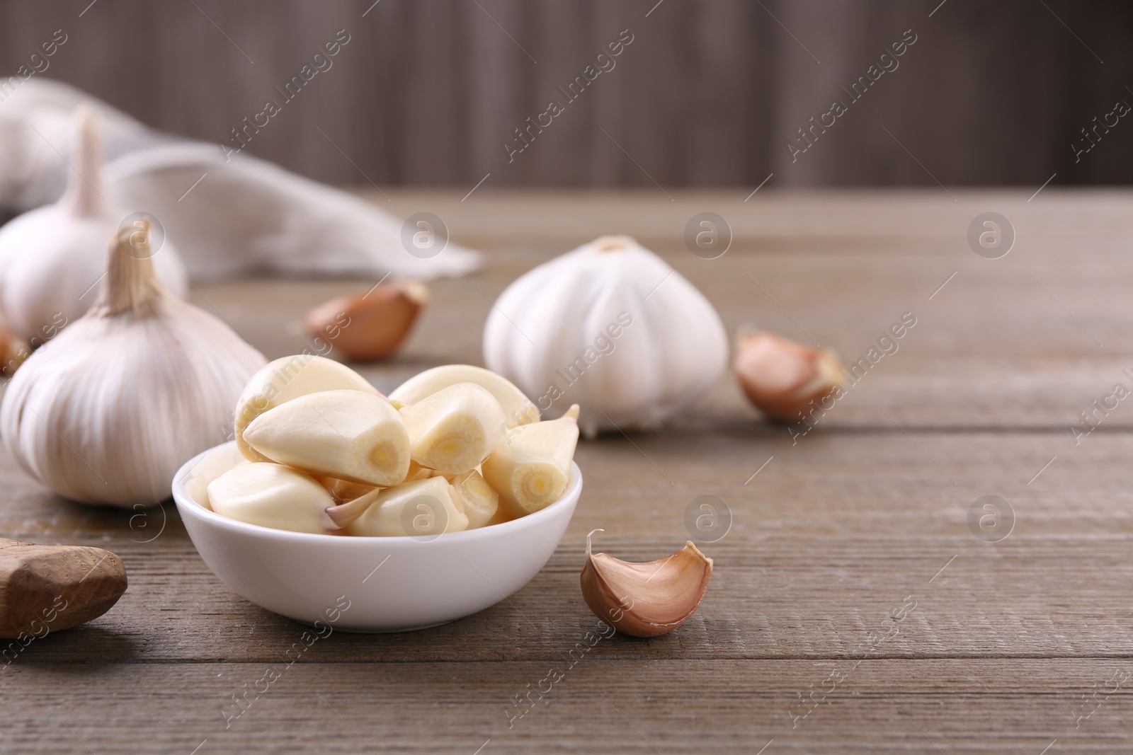 Photo of Aromatic garlic cloves and bulbs on wooden table. Space for text