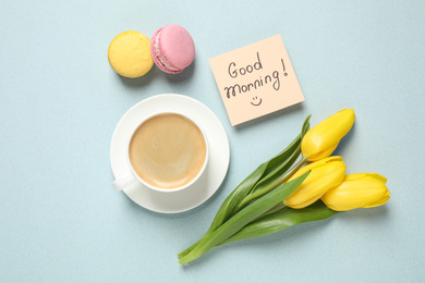 Photo of Delicious coffee, macarons, flowers and card with GOOD MORNING wish on light background, flat lay