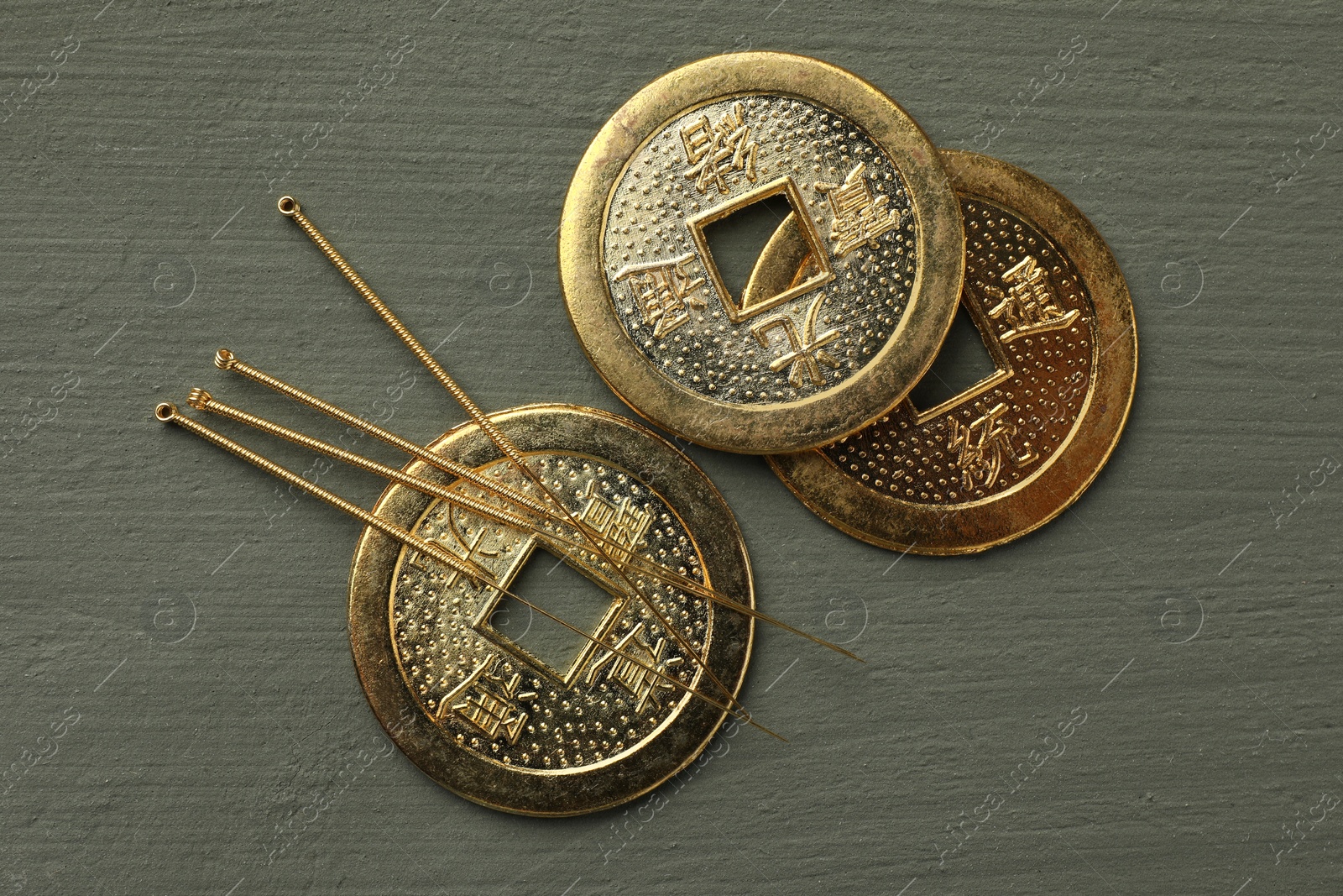 Photo of Acupuncture needles and antique Chinese coins on grey wooden table, flat lay