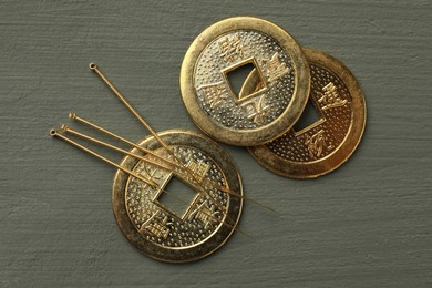 Photo of Acupuncture needles and antique Chinese coins on grey wooden table, flat lay