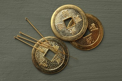 Acupuncture needles and antique Chinese coins on grey wooden table, flat lay