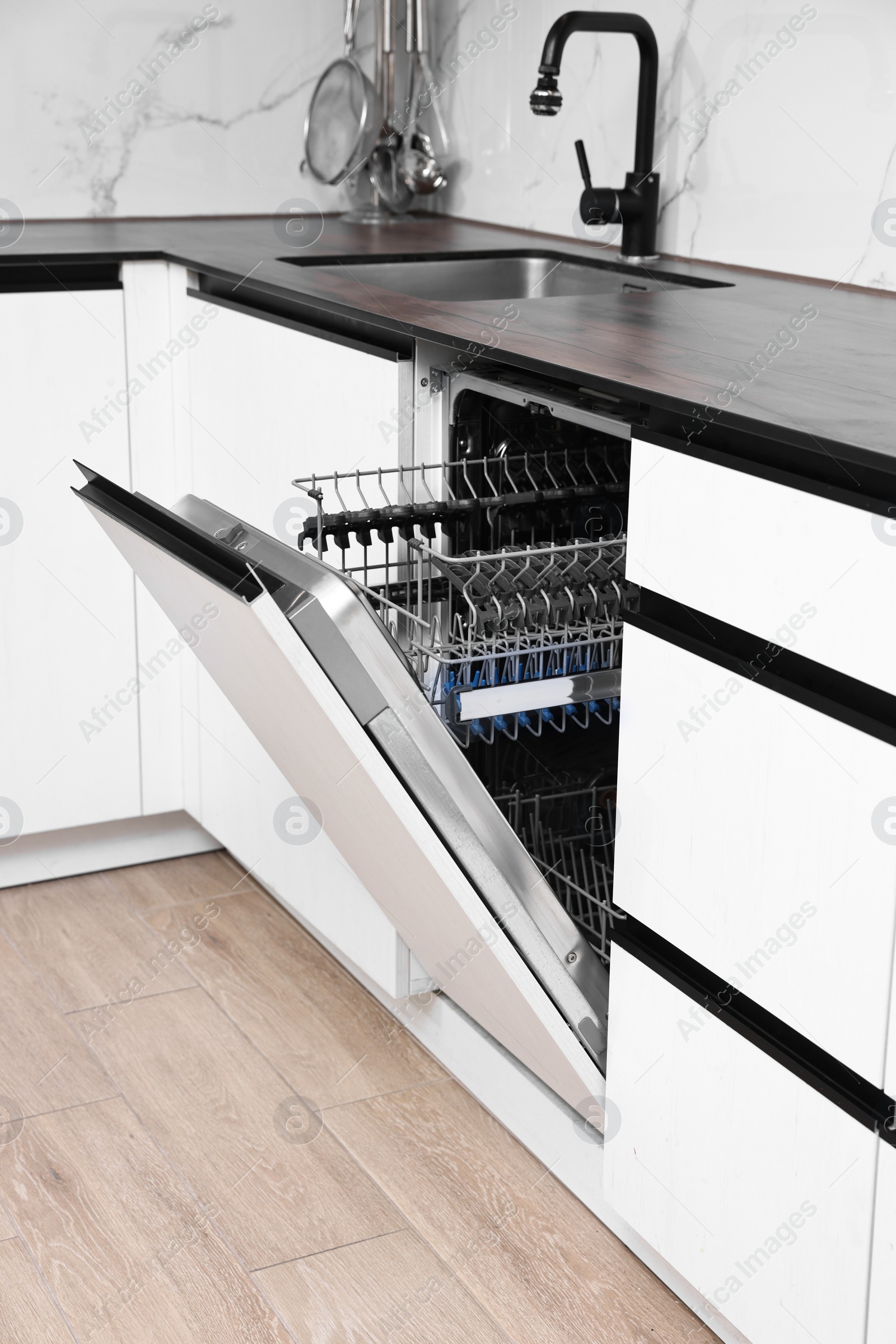 Photo of Built-in dishwasher with open door indoors. Home appliance