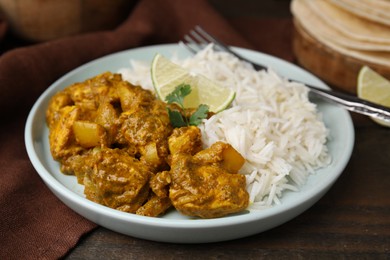 Photo of Delicious chicken curry with rice on wooden table, closeup