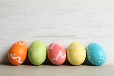 Colorful painted Easter eggs on table against wooden background, space for text