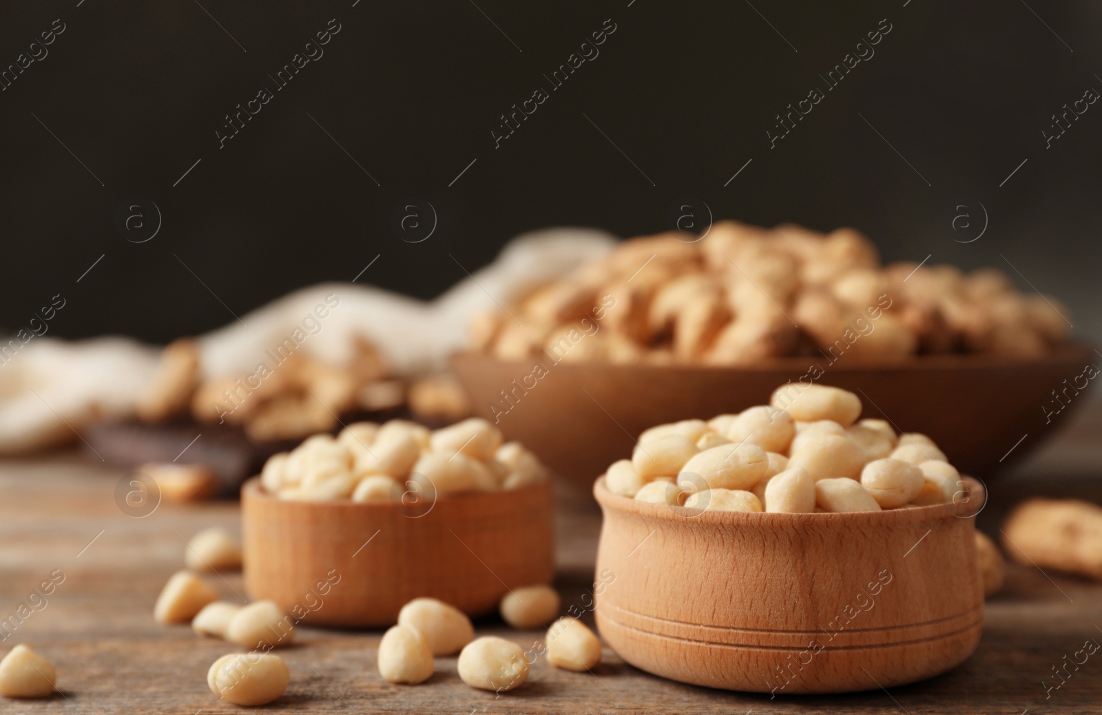 Photo of Shelled peanuts in wooden bowls on table