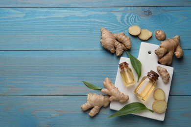 Photo of Glass bottles of essential oil and ginger root on light blue wooden table, flat lay. Space for text