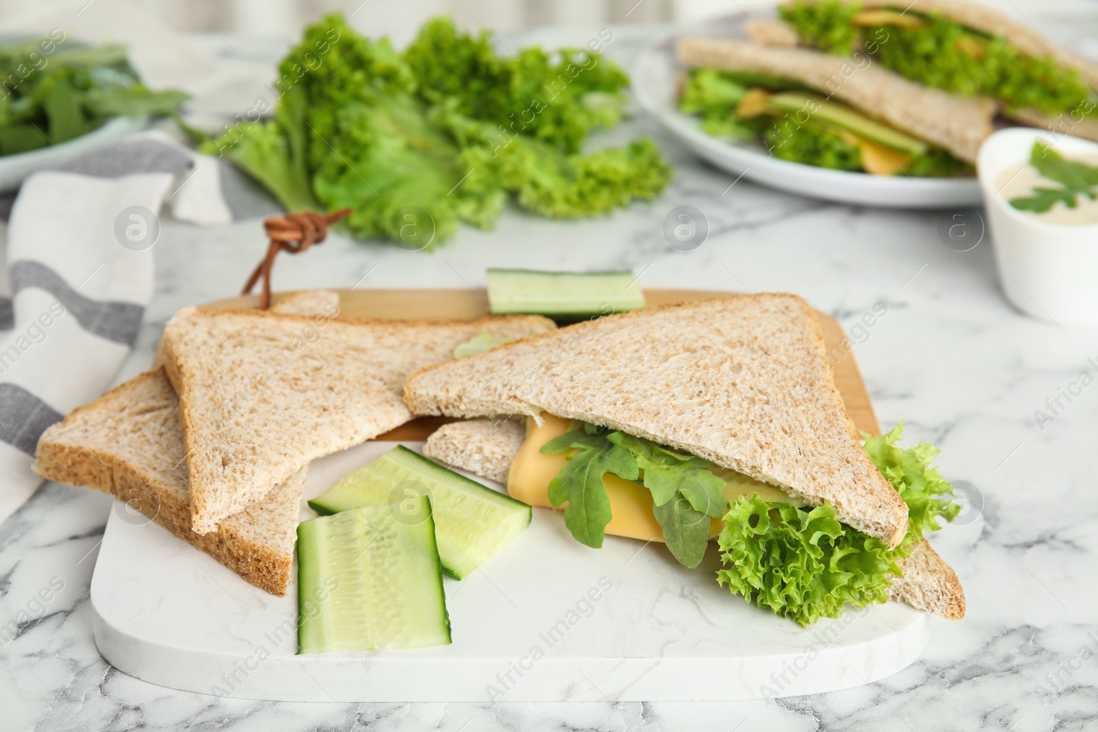 Photo of Tasty fresh sandwiches greens and cheese on white marble table, closeup