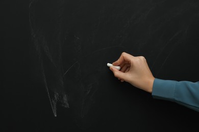 Photo of Woman with white chalk near blackboard, closeup. Space for text