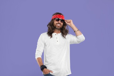 Photo of Stylish hippie man in sunglasses on violet background