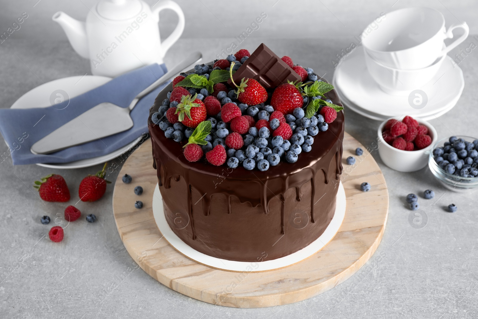 Photo of Freshly made delicious chocolate cake decorated with berries on white table