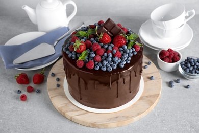 Photo of Freshly made delicious chocolate cake decorated with berries on white table