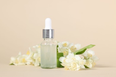 Essential oil in bottle and beautiful jasmine flowers on beige background