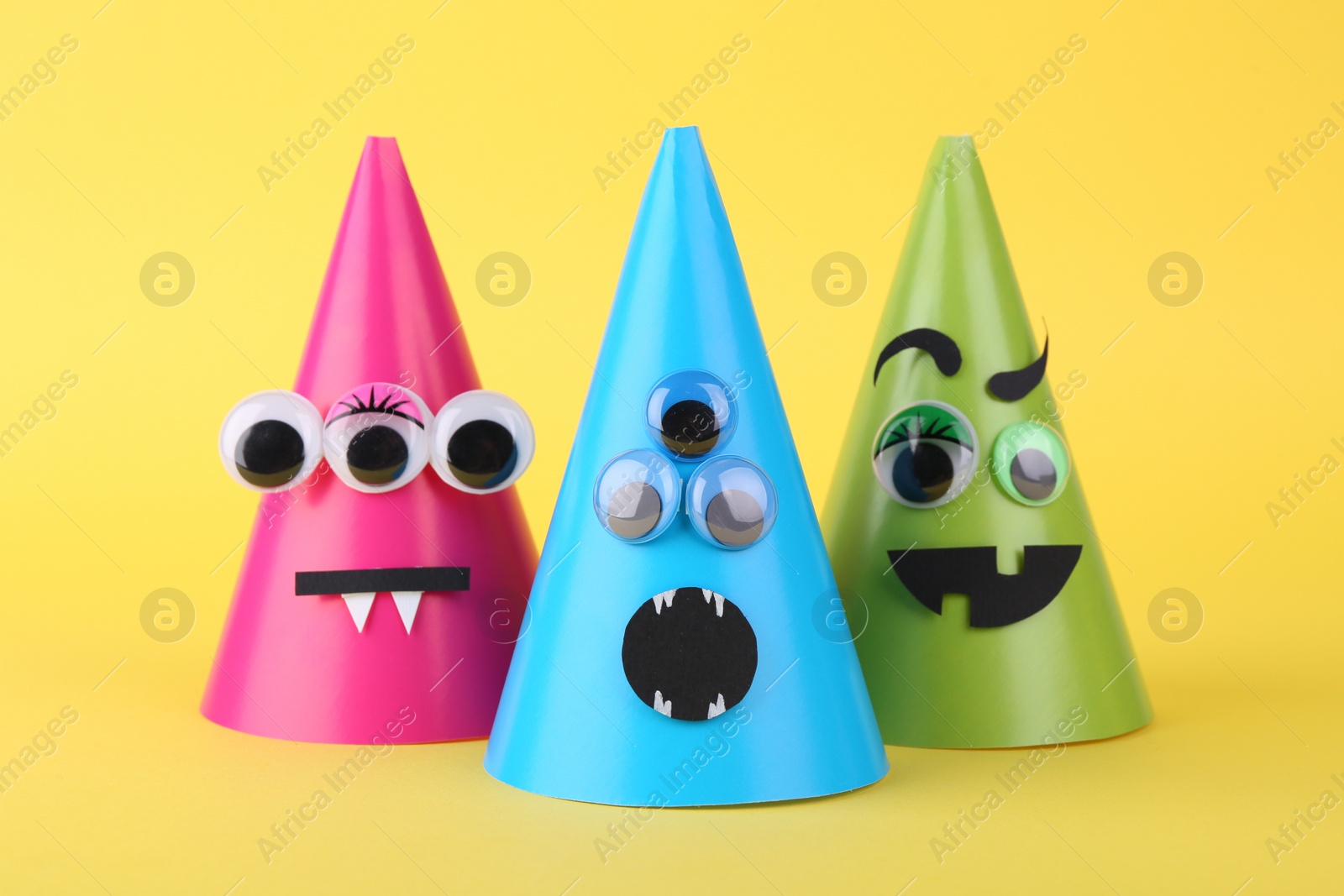 Photo of Spooky paper monsters on yellow background. Halloween decoration