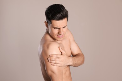 Photo of Man suffering from shoulder pain on beige background