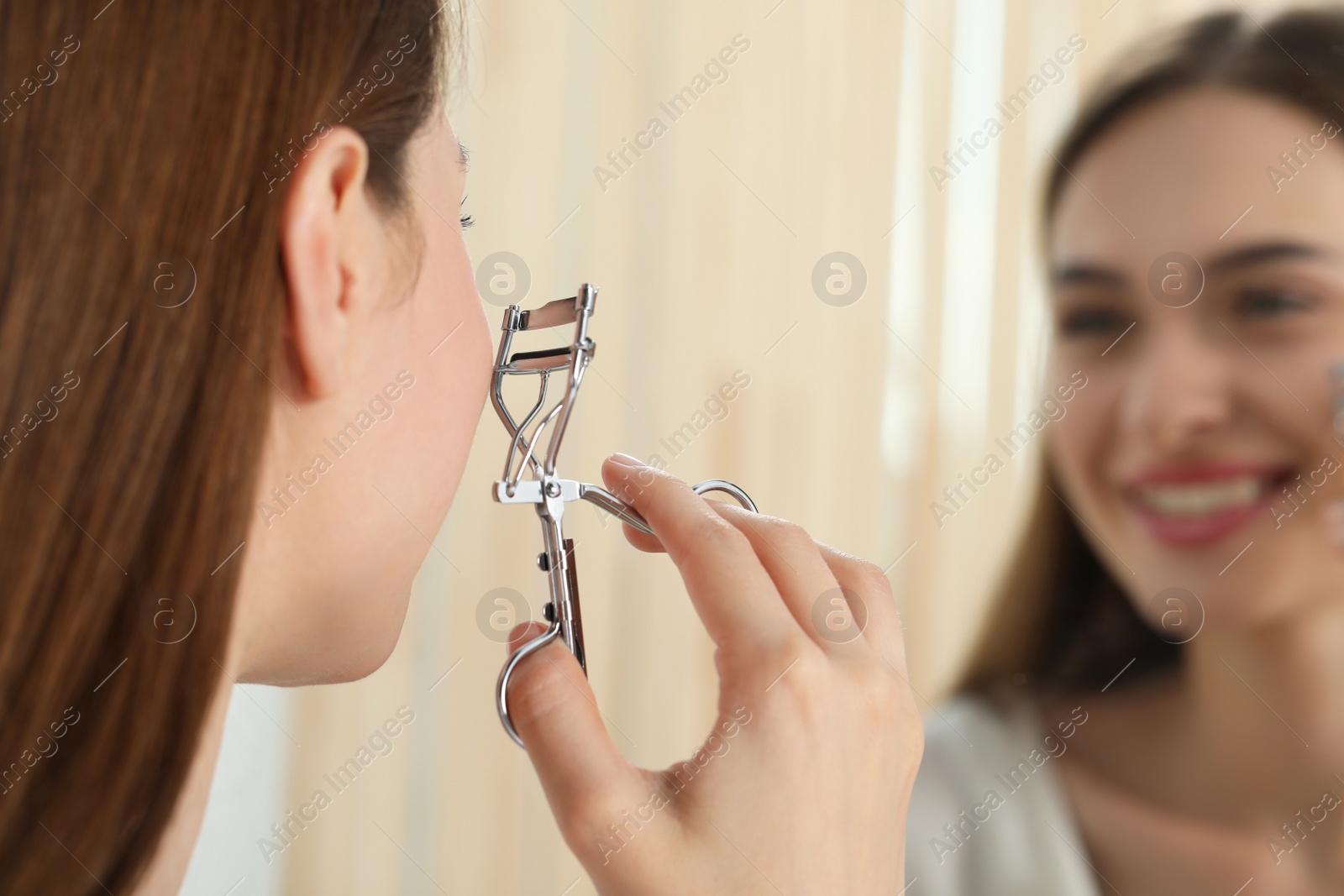Photo of Woman with eyelash curler near mirror, closeup. Space for text