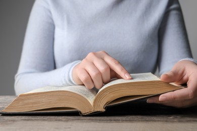 Photo of Woman reading Bible at wooden table, closeup