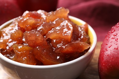 Photo of Bowl of delicious apple jam and fresh fruits on wooden table, closeup