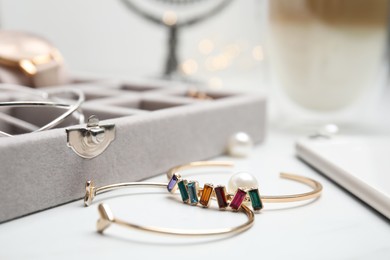 Photo of Beautiful bracelets and jewelry box on white table, closeup