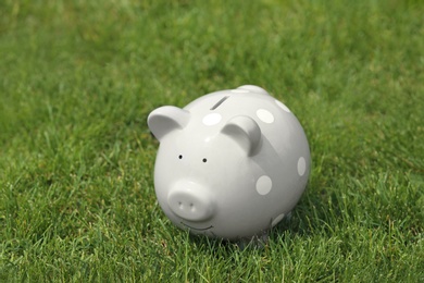 Photo of Cute piggy bank on green grass outdoors