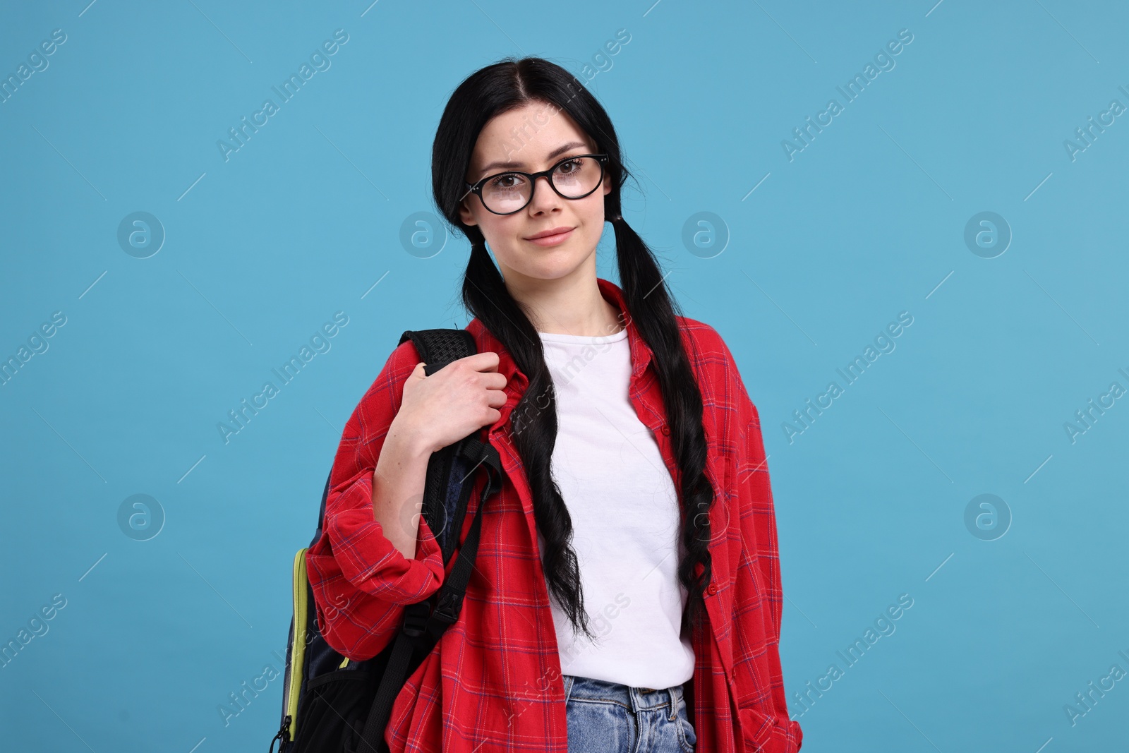 Photo of Student in glasses with backpack on light blue background