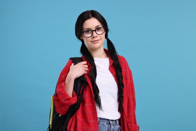 Student in glasses with backpack on light blue background