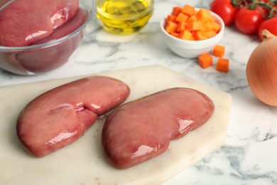 Photo of Fresh raw pork kidneys and ingredients on white marble table