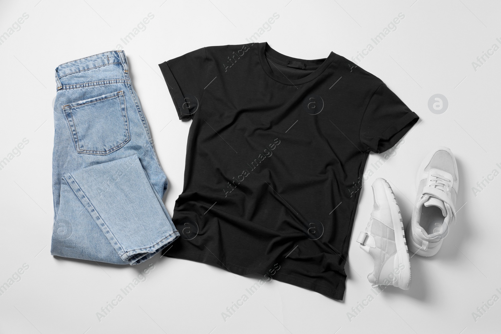 Photo of Stylish t-shirt, jeans and sneakers on white background, flat lay