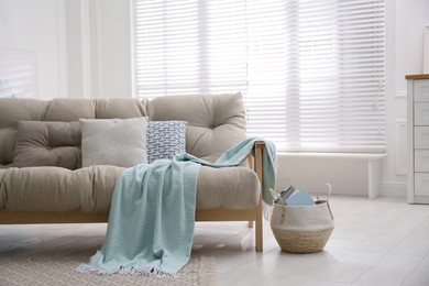 Modern living room interior with comfortable sofa and light blue blanket