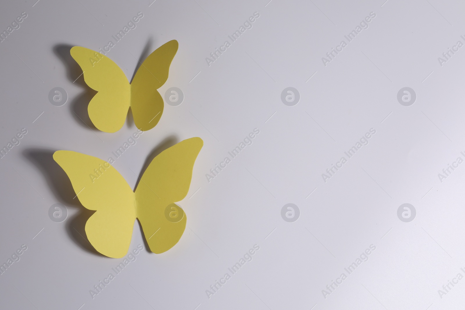 Photo of Yellow paper butterflies on light background, top view. Space for text