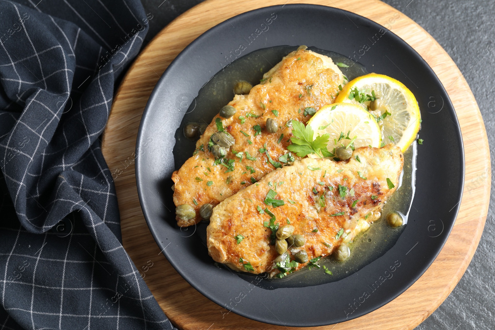 Photo of Delicious chicken piccata on black table, top view