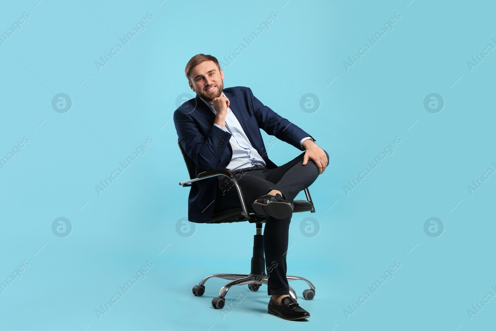 Photo of Young businessman sitting in comfortable office chair on turquoise background