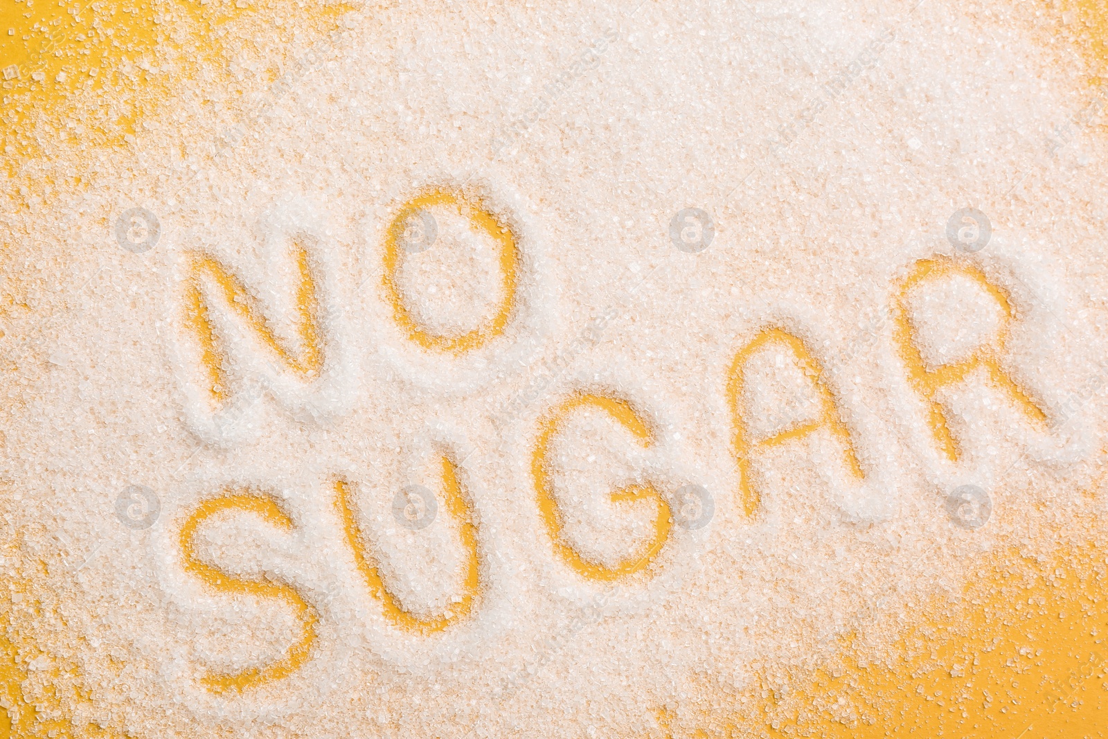 Photo of Phrase No Sugar made of granules on yellow background, flat lay