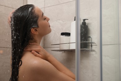 Photo of Woman washing hair in shower stall indoors