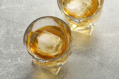Photo of Tasty whiskey in glasses on grey table, closeup