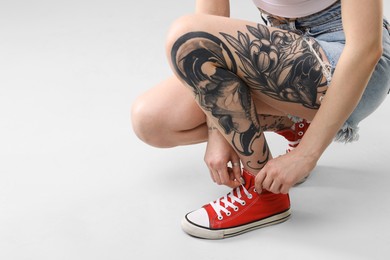 Photo of Woman with cool tattoos on light background, closeup. Space for text